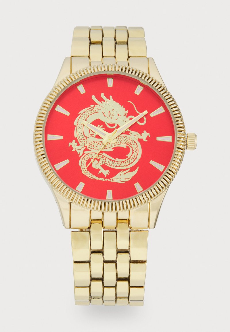 Gold metal wristwatch with a round face, red dial featuring a dragon design, and gold-tone markers. Bracelet style band with linked segments.