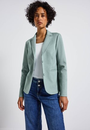 Blazer vert menthe avec une coupe ajustée, design à un bouton, deux boutons et poches avant, associé à un jean large bleu foncé.