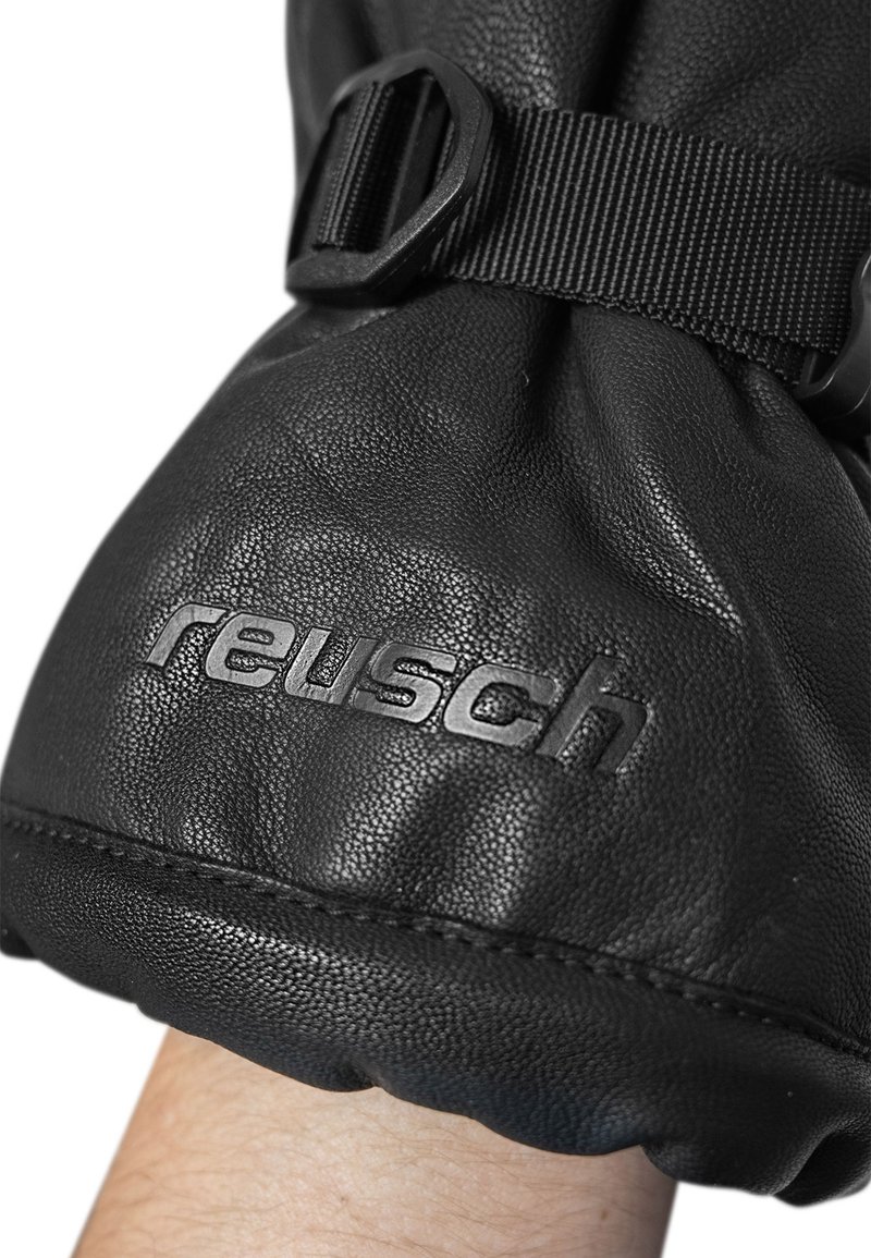 Schwarze Lederhandschuhe mit einer strukturierten Oberfläche, ausgestattet mit einem Riemen und einer Schnalle zur Anpassung. Das Markenlogo "Reusch" ist deutlich sichtbar.
