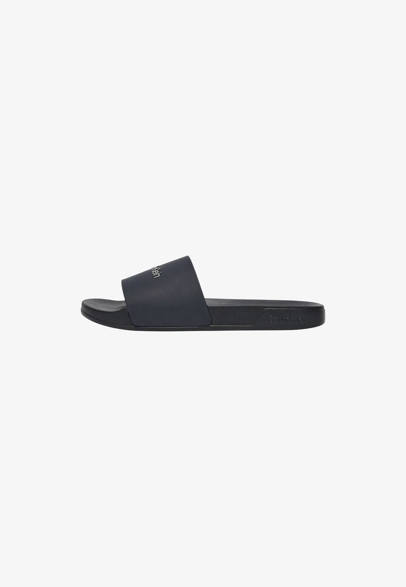 Sandale noire à bande large sur le pied, avec un logo embossé sur le côté et le dessus de la bride.