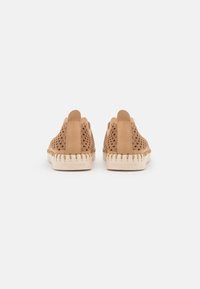 Scarpe perforate color tan con finitura in pelle liscia e intagli decorativi. Presentano una suola testurizzata e un tacco con marchio.