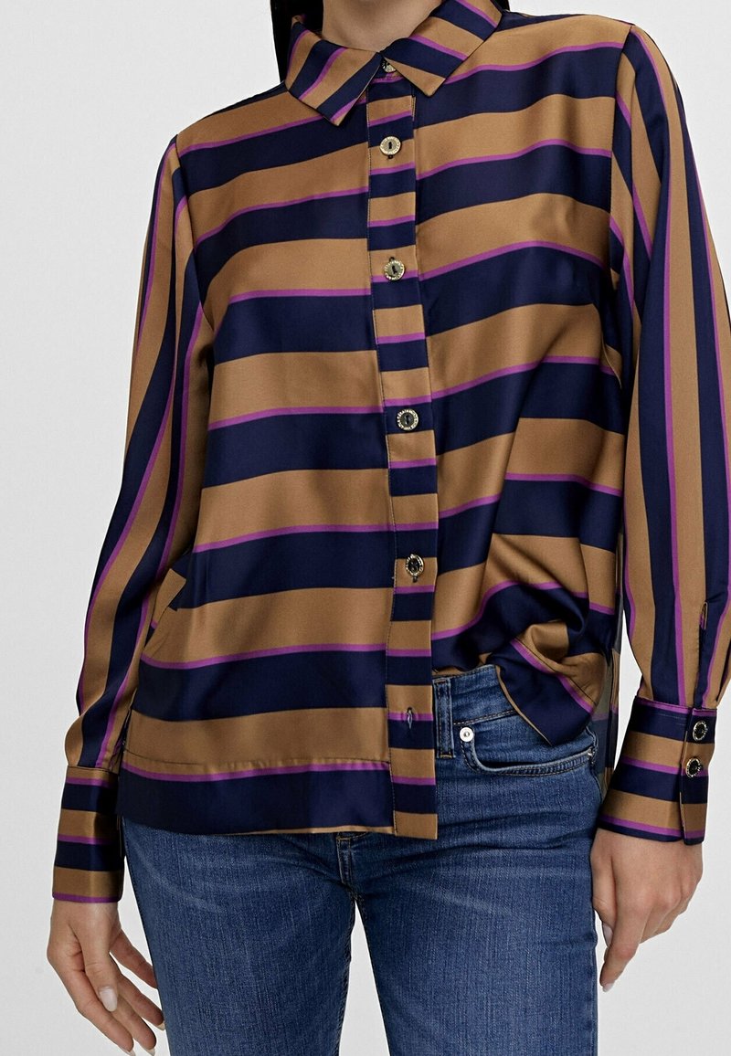 Silkeskjorta med krage, med horisontella ränder i brunt, marinblått och lila, knappstängning fram med matchande knappar och långa ärmar.