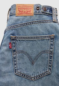 Ανοιχτό μπλε τζιν με δερμάτινο ταμπελάκι που φέρει το "Levi Strauss & Co." και κόκκινη ετικέτα στην πίσω τσέπη με κλασικό σχέδιο ραφής.