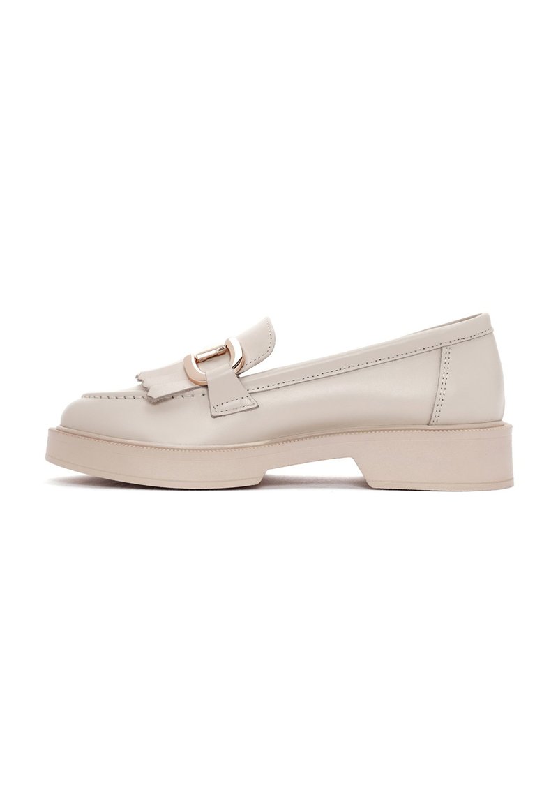 Mocassins en cuir beige avec un bout arrondi, semelle en caoutchouc plate et une boucle décorative sur le devant. Design épuré avec un minimum de coutures.