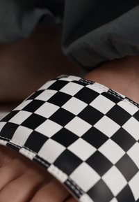 Black and white checkered wristband made of textured synthetic material, with visible stitching and a flexible design.