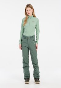 Lichtgroene quarter-zip top en bijpassende skibroek met een getailleerde taille, meerdere zakken en een gladde textuur. Bruine hardwareaccenten zichtbaar.