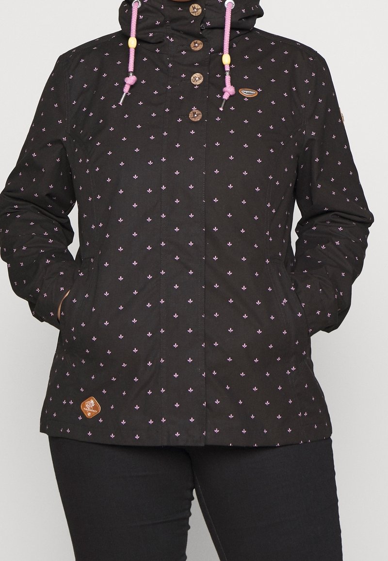 Czarna kurtka w kwiatowy wzór w różowym kolorze, z zamknięciami na guziki, regulowanym kapturem z różowymi sznurkami oraz brązową naszywką.
