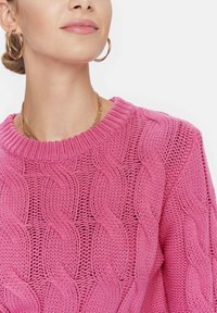 Pullover rosa lavorato a maglia con motivo a treccia e scollatura rotonda a coste. La trama è morbida e traspirante, adatta per un abbigliamento casual.