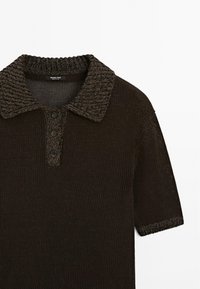 Brun stickad pikétröja med korta ärmar, texturerad krage och treknapprad framtill. Tillverkad av ett andningsbart, lätt material.