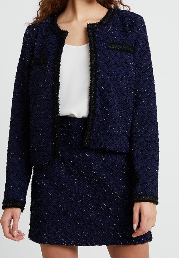 Ensemble veste et jupe bleu marine texturé avec un motif en losange, bordé de noir. Présente une coupe carrée et deux poches avant.