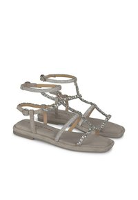 Graue flache Sandalen mit mehreren Riemen. Die Riemen sind mit silbernen Akzenten und Strasssteinen verziert. Weicher Stoff, offenes Zehen-Design, verstellbare Riemen am Knöchel.