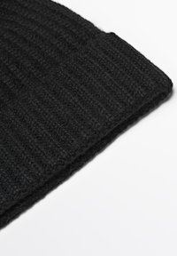 Black knitted beanie with a ribbed texture. Material appears soft and thick, with a folded edge for added warmth and style.