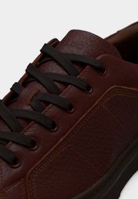 Bague en cuir marron avec surface texturée, lacets foncés et surpiqûres contrastantes. Bout arrondi et semelle en caoutchouc profil bas.