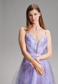 Lavendel Tüllkleid mit floralem Muster, V-Ausschnitt, dünnen Schulterträgern und taillierter Oberweite. Der Rock hat eine mehrlagige, fließende Textur.