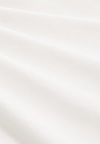Zijdeachtig wit stof met zachte plooien en subtiele diagonale schaduwen, die de textuur en de delicate draping accentueren.