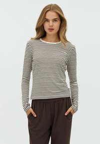 Long-sleeve top in cream with dark brown horizontal stripes, featuring a round neck and slim fit design, paired with brown relaxed-fit pants.