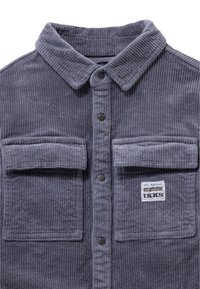 Szara koszula z kordurojowej tkaniny, z zapięciem na guziki z przodu, dwiema kieszeniami na piersi i kołnierzykiem. Posiada metkę w prawym dolnym rogu. Teksturowany, prążkowany materiał.