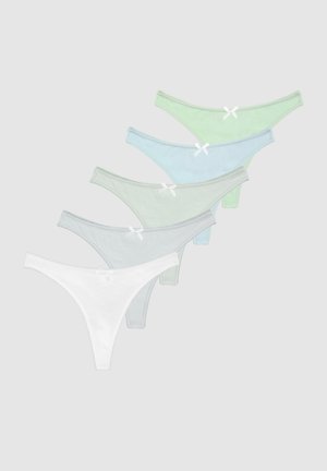 Jeune femme aux longs cheveux blonds portant un crop top vert clair et une culotte rayée assortie, debout devant un fond clair uni.