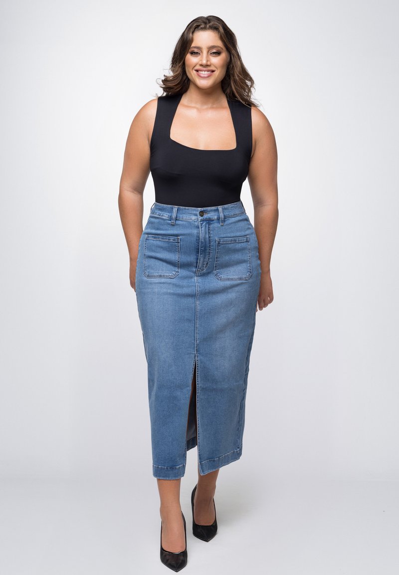 Jeansrok met een voorkeursplit, hoge taille en twee achterzakken. Gecombineerd met een zwart aansluitend body en zwarte puntige hakken.