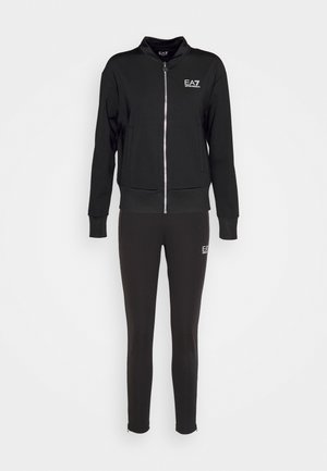 Zwarte atletische set, bestaande uit een rits bomberjack met geribde manchetten en bijpassende strakke leggings. De stof is glad en heeft logo-accenten.