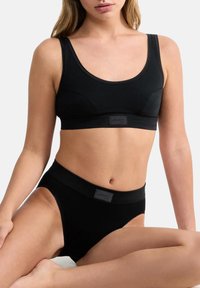 Zwarte bralette en set met hoge taille slips. Glad materiaal, naadloos ontwerp, subtiele logo-accenten en ronde halslijn op de bralette.
