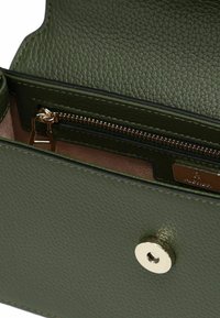 Portafoglio in pelle verde con texture, dotato di un compartimento con cerniera e chiusura a scatto in metallo lucido. All'interno presenta una fodera rosa e un'etichetta del marchio.