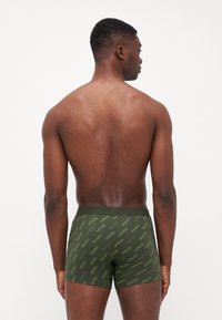 Gröna boxerkalsonger med upprepat "Levi's"-logomönster, med en mjuk textur och åtsittande design. Sedd bakifrån.