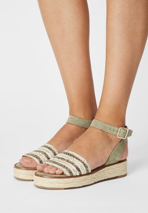 Lysgrønne suedestøvler med stribede vævede stropper, flettet espadrille-platform, justerbar ankelrem og åben tå-design.