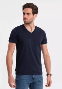 Námořnická modrá v-neck tričko z měkké látky, krátké rukávy a slim fit střih. V kombinaci s světlými modrými džíny.
