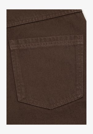 Zbliżenie na brązową kieszeń z tkaniny z widocznym przeszyciem na teksturowanym denimu lub materiale typu twill.