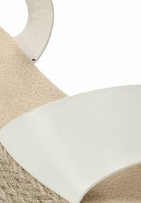 Sandalia de ante beige con una amplia tira de cuero blanco, textura suave, diseño de punta abierta y suela de yute natural.