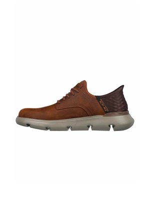 Zapatilla de piel marrón con un tacón texturizado de color marrón oscuro, con punta redonda, suela de goma gris y cordones marrones.