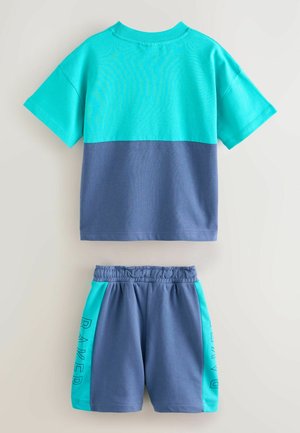 Sæt til børn bestående af en turkise og mørkeblå T-shirt med korte ærmer og matchende shorts med turkise sidestykker og tekst.