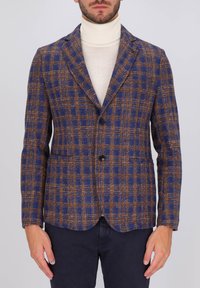 Blazer in tweed a quadri blu e marrone, con rever a punta, due bottoni e tasche aperte. Tessuto morbido, vestibilità sartoriale.