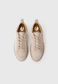 Beige nubuk sneaker hat szemgyűrűkkel, texturált felülettel és húzófüllel. Sárga talpbetéten szárnyas emblémás logó található. Lapos gumitalp.