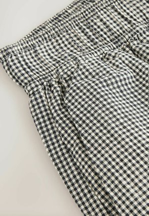 Gingham-patterned fabric in black and cream, featuring an elastic waist and slightly gathered detailing for a textured appearance.