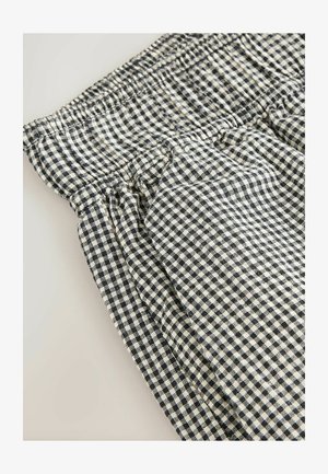 Gingham-patterned fabric in black and cream, featuring an elastic waist and slightly gathered detailing for a textured appearance.