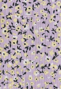 Květinová tkanina s fialovým pozadím a černými a žlutými květinovými vzory. Měkká textura s žebrovaným designem a rozptýlenými listy.