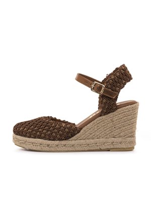 Sandalia cuña marrón tejida con correa al tobillo y hebilla, tacón envuelto en yute, parte superior de tela texturizada, puntera redonda y tono natural.