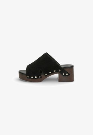 Mocassino aperto sul retro in suede nero con tacco a blocco in legno e borchie argentate lungo il bordo, vista laterale su sfondo bianco.