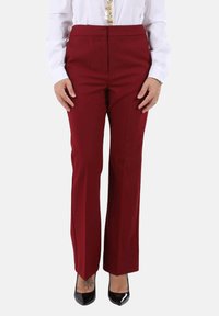 Pantaloni su misura color borgogna con design a gamba dritta, texture liscia e vita media, abbinati a tacchi alti neri.