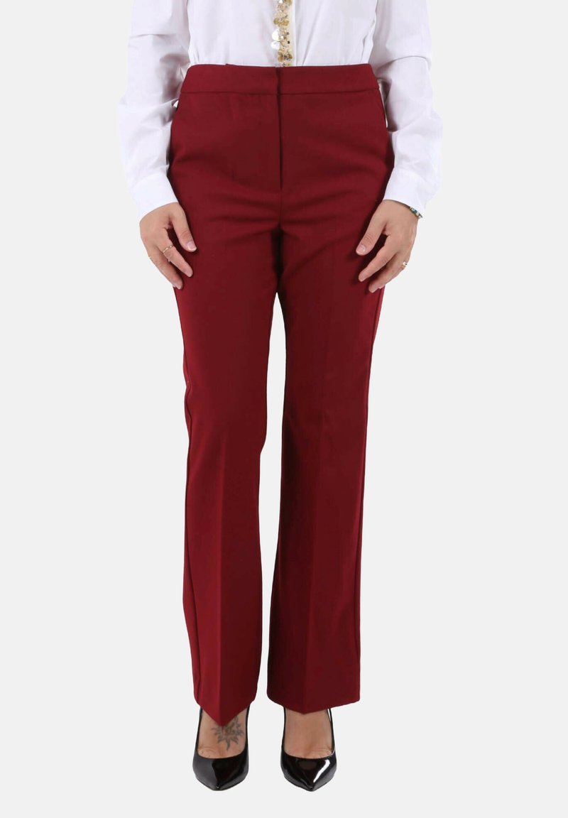 Pantaloni su misura color borgogna con design a gamba dritta, texture liscia e vita media, abbinati a tacchi alti neri.