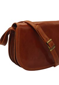 Sac à bandoulière en cuir marron avec une finition lisse, de forme arrondie, des coutures décoratives et une sangle ajustable avec une boucle en laiton.