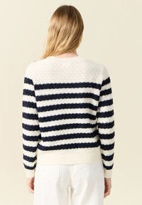 Maglione a righe con colori blu navy e crema, motivo a maglia lavorata con texture, polsini e orlo a costine, con dettagli a bottoni sulla spalla.