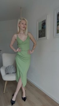 Green, knee-length dress with a wrap design and V-neck, paired with black pointed-toe heels. Smooth texture and high slit on the side.