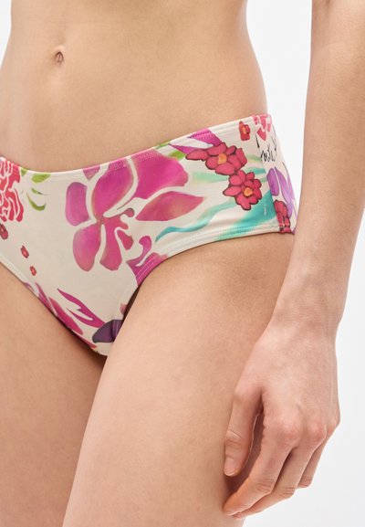 Gros plan sur une personne portant un bas de bikini à motif floral dans des tons de rose, rouge et violet, avec une main visible et le ventre nu.