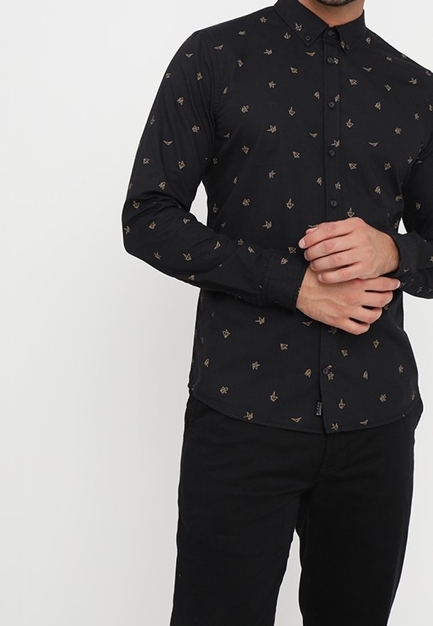 Zwarte lange mouwen shirt met een subtiel beige patroon van pijlen en geometrische vormen. Heeft een kraag en knopen aan de voorkant.