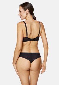 Czarny komplet bielizny z gładkim biustonoszem na plecach z regulowanymi ramiączkami i dopasowanymi przezroczystymi majtkami z tyłu. Subtelne falowane wykończenia.
