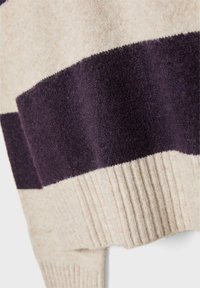 Pulover iz pletenine z širokimi kremnimi in temno vijoličastimi črtami, rebrastimi manšetami in mehko teksturo. Material deluje toplo in udobno.