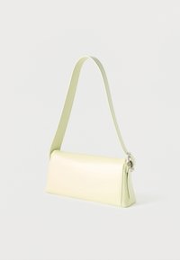 Ορθογώνια ώμου τσάντα σε ανοιχτό κίτρινο χρώμα με μακρύ λουρί και ασημένιες λεπτομέρειες, τοποθετημένη πάνω σε απλό φωτεινό φόντο.